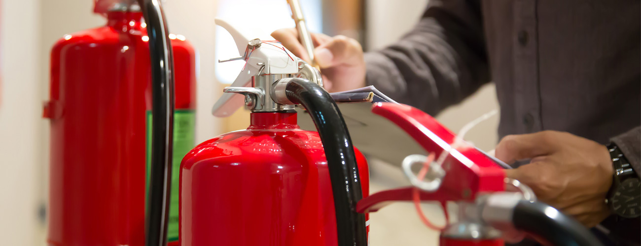Fire Risk Assessments Bristol. Fire risk assessor examining extinguishers.