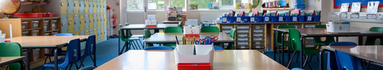 Classroom interior with desks, chairs, and storage for educational materials.