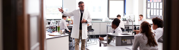 A teacher explaining concepts to students in a laboratory classroom setting.